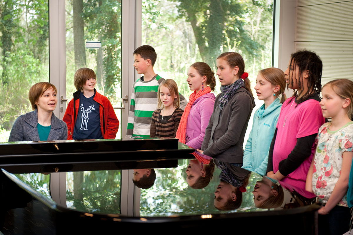 Musiklehrerin am Klavier und Jugendchor