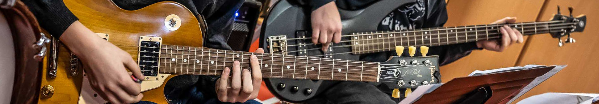 Zwei Jugendliche spielen E-Gitarre und E-Bass während einer Bigband-Probe