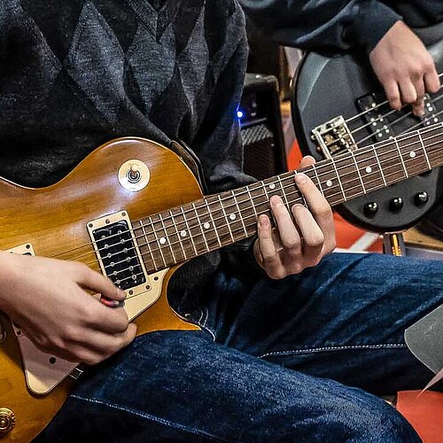 Zwei Jugendliche spielen E-Gitarre und E-Bass während einer Bigband-Probe