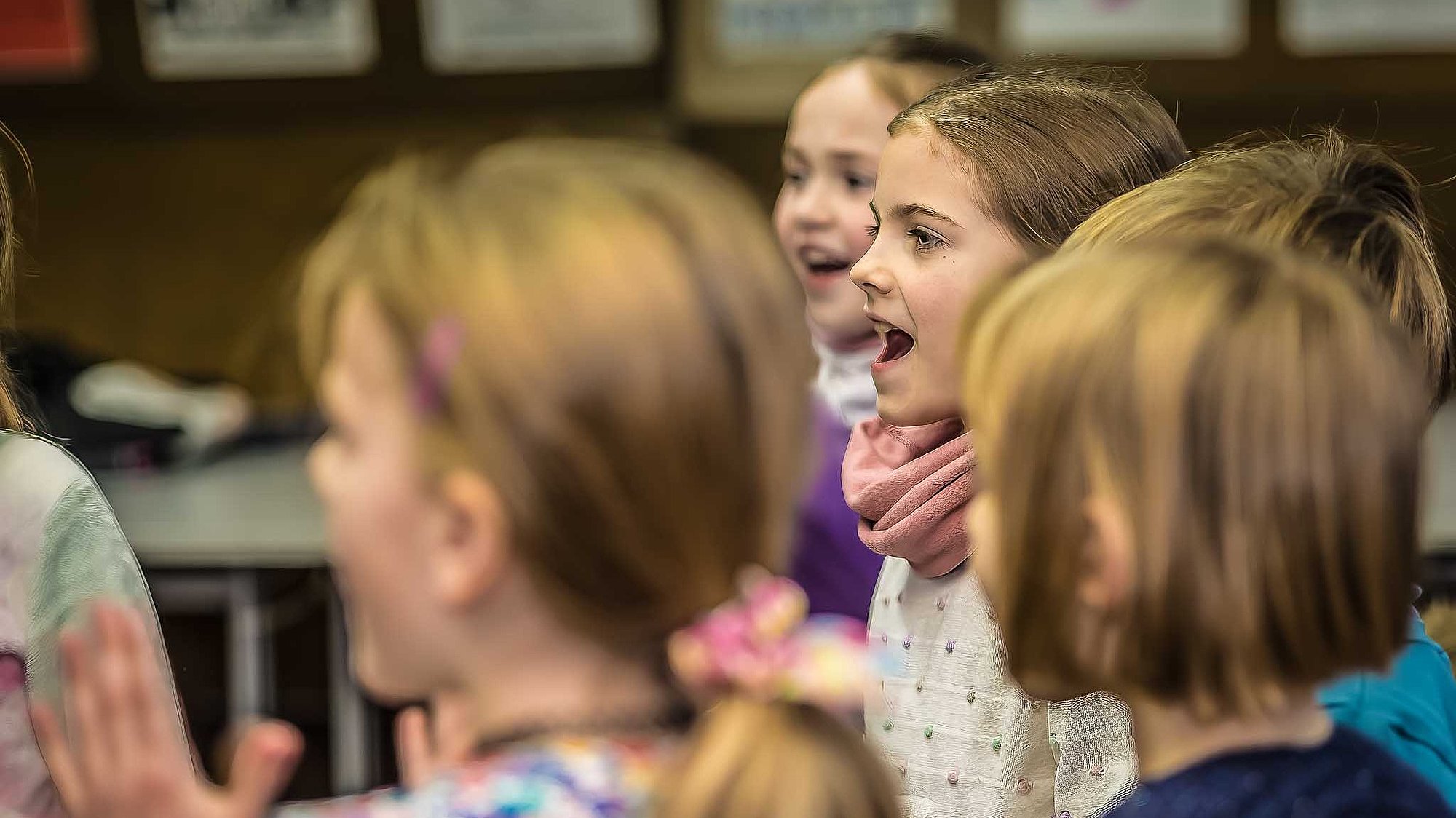 Grundschulkinder stehen im Kreis und singen und klatschen im Chor