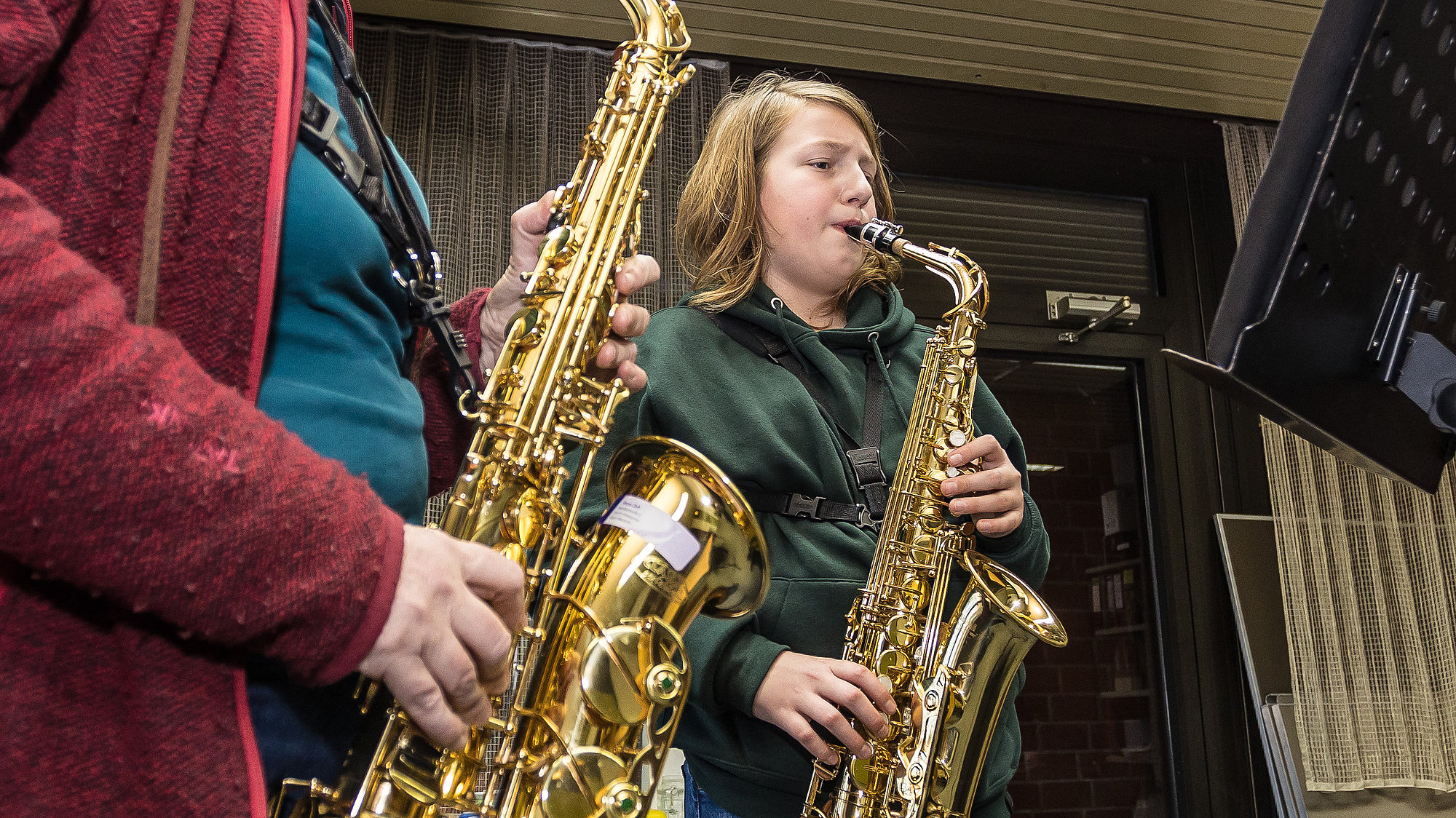 Musiklehrerin und jugendlicher Schüler spielen gemeinsam Saxofon.